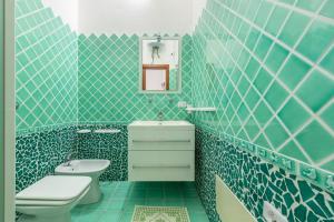 Baño de azulejos azules con aseo y lavamanos en Villa Chiara en SantʼAntìoco