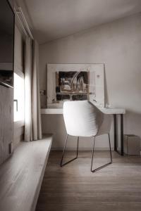 una sedia bianca seduta in una stanza con scrivania di Locanda MaMaGiò a Valdobbiadene