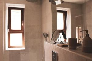 ein Badezimmer mit zwei Fenstern und einer Ablage mit Spiegel in der Unterkunft Salthouse Portugal - Exclusive East Apartment in Aljezur