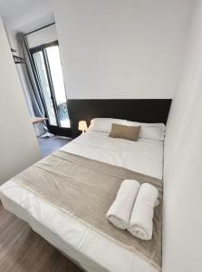 a bedroom with a white bed with two towels on it at Casa de huéspedes Mi lla in Madrid