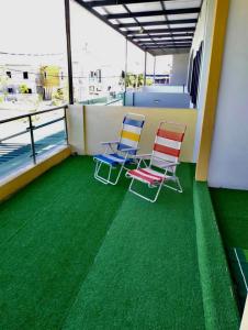 2 sillas en un balcón con suelo verde en JOE Homestay en Alor Setar