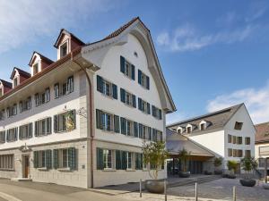 Un grand bâtiment blanc avec volets verts dans l'établissement CASPAR Swiss Quality Hotel, à Muri