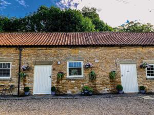 um edifício de tijolos com duas portas brancas e flores em Old Orchard Cottage, Wykeham em Scarborough
