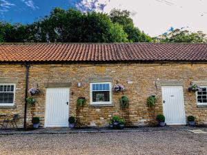 a brick building with two white doors and flowers at Old Orchard Cottage, Wykeham in Scarborough