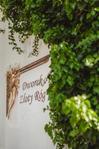 un panneau sur le côté d'un bâtiment avec des feuilles vertes dans l'établissement Dworek Złoty Róg Hotel i Restauracja, à Cracovie