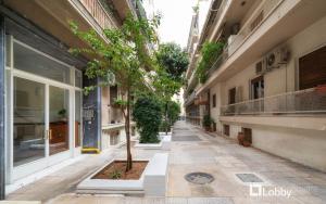 an empty alley with a tree in the middle of a building at Embassy Studio by LobbySquare in Athens