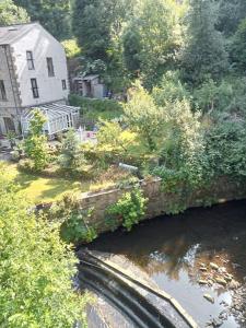 an old stone bridge over a river with a house at Treetops & Viaducts; open plan two-bed apartment in Walsden