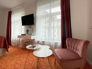 ein Wohnzimmer mit einem Stuhl, einem Tisch und einem Fenster in der Unterkunft ART HOTEL HOUSE ONE in Baden-Baden