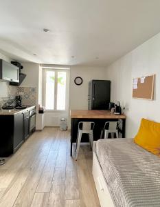 1 dormitorio con 1 cama y cocina con mesa en Charmant studio au coeur du centre ville, en Chagny