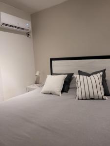 um quarto com uma grande cama branca com almofadas em BE Apartments Vicente em Mendoza