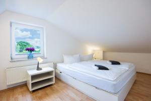 Habitación blanca con cama y ventana en Die Küstenjungs - 3 strandnahe Ferienhäuser OFC 22 en Diedrichshagen