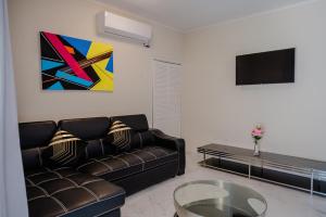 a living room with a leather couch and a tv at Modern 1-bedroom-apartment 2 km from Eagle beach in Palm-Eagle Beach