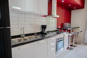 Modern 1-bedroom-apartment 2 km from Eagle beach في شاطئ بالم إيغل: مطبخ مع أجهزة بيضاء وجدران حمراء