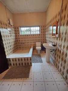 a bathroom with a tub and a toilet and a sink at Tumi Hostel in Kumasi