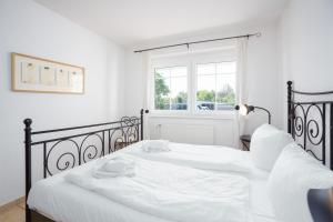 una camera con due letti con lenzuola bianche e una finestra di Strand Domizil Wohnung 2 a Haffkrug