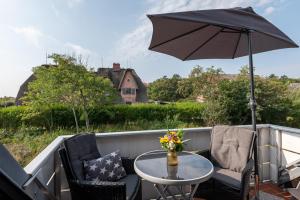 einen Terrassentisch und Stühle mit Sonnenschirm in der Unterkunft Jutta, App 6 in Wenningstedt-Braderup