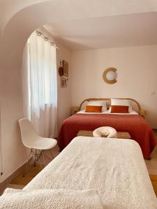 1 Schlafzimmer mit 2 Betten und einem weißen Stuhl in der Unterkunft Casa Ostara in Condorcet