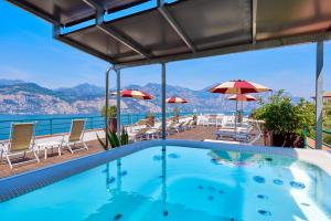 a swimming pool with chairs and umbrellas at Hotel Villa Smeralda in Malcesine