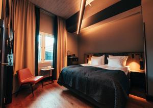 a bedroom with a bed and a chair and a window at Hotel Mestari in Helsinki