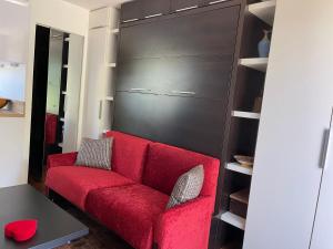 a red couch in a room with a black closet at Studio dans résidence privée à 15 mn de cannes in Le Cannet