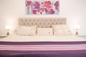 una camera da letto con un grande letto bianco con una coperta viola di Augusta Deluxe a Salta