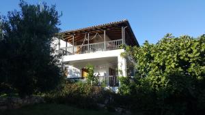 a white building with a balcony and trees at Chelidonia in Steni Vala Alonissos