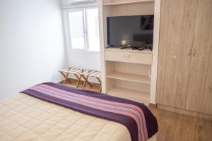 sypialnia z łóżkiem i telewizorem z płaskim ekranem w obiekcie Augusta Deluxe w mieście Salta