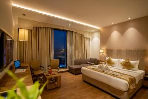 a hotel room with a bed and a living room at Celebrant Hotel in Varanasi