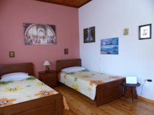 two beds in a room with pink walls and wooden floors at The Writers House in Ano Pavliana in Áno Pavliána