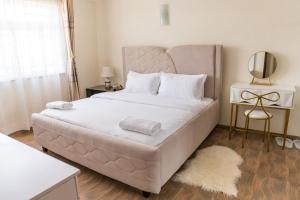 Milimani Cosy Condo في ناكورو: غرفة نوم بسرير كبير مع شراشف بيضاء ومرآة