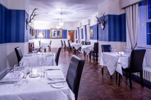 Dalmunzie Castle Hotel في غلين شي: غرفة طعام مع طاولات بيضاء وكراسي سوداء