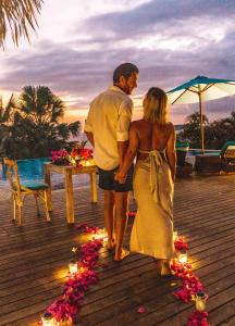 a man and a woman standing on a deck with a table with flowers at The Endless Summer Resort in Bumbang