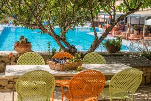 
a picnic table and chairs in front of a pool at Koukounaria Hotel & Suites in Alykes
