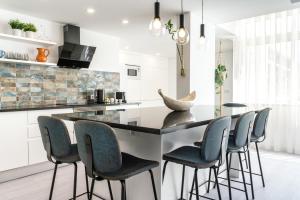 a kitchen with a black counter and blue chairs at Privilege Deluxe Apartment Casa Mãe, Faro in Faro