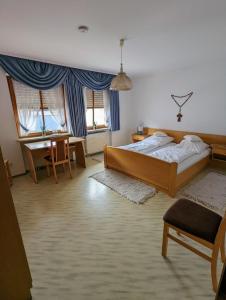 a bedroom with a bed and a desk and two windows at Cafe-Bäckerei-Pension Weigl in Oberviechtach