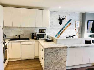 a kitchen with white cabinets and a brick wall at Hotham 3 Bedroom Apt - 24 Lawlers in Mount Hotham