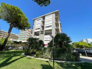 een hoog wit appartementencomplex met palmbomen in een park bij Laguna Grande - Appartamenti in Bibione