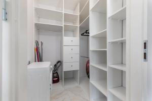 a white walk in closet with white shelves at ECRU Spacious Premium Apartment with City View in Warsaw WWA4 in Warsaw