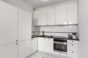 a white kitchen with white cabinets and an oven at ECRU Spacious Premium Apartment with City View in Warsaw WWA4 in Warsaw