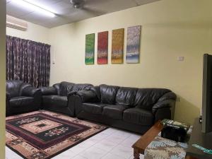 a living room with a black leather couch at HomestayMuslim Di Teluk Intan in Teluk Intan