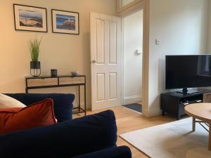 a living room with a blue couch and a flat screen tv at Modern 3 bed house in the heart of Morpeth town. in Morpeth
