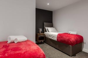 um quarto com 2 camas e um cobertor vermelho em Victoria Apt - 2 bedroom Parking Wi-Fi Workers em Hyde