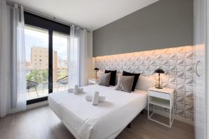 una camera da letto con un grande letto bianco e una grande finestra di ChicStays Apartment Vila Olímpica a Barcellona