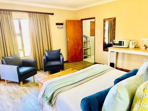 a hotel room with a bed and two chairs at Travalia Guest Farm in Nelspoort