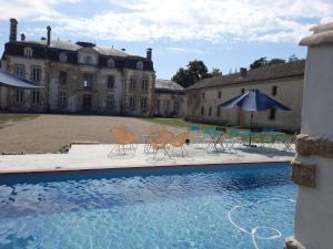 una piscina con sillas y sombrillas frente a un edificio en La métairie du château le Vignau, en Le Vignau