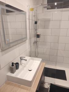 La salle de bains blanche est pourvue d'un lavabo et d'une douche. dans l'établissement Maison de village avec vue sur les montagnes, à Bigorno