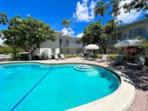a swimming pool with chairs and umbrellas next to a house at Royal Palms Resort & Spa in Fort Lauderdale