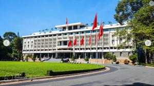 un bâtiment blanc avec des drapeaux rouges devant lui dans l'établissement Felix Hotel, à Hô-Chi-Minh-Ville