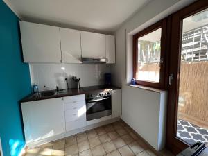 a kitchen with white cabinets and a sink and a window at Ferienwohnung Coco in Schallstadt