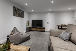 a living room with a couch and a flat screen tv at Victoria Place - 3-bed apartment, parking, Wi-Fi in Hyde